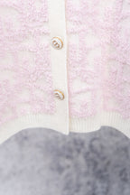 Pale pink textured cardigan with white ribbed hem and button placket