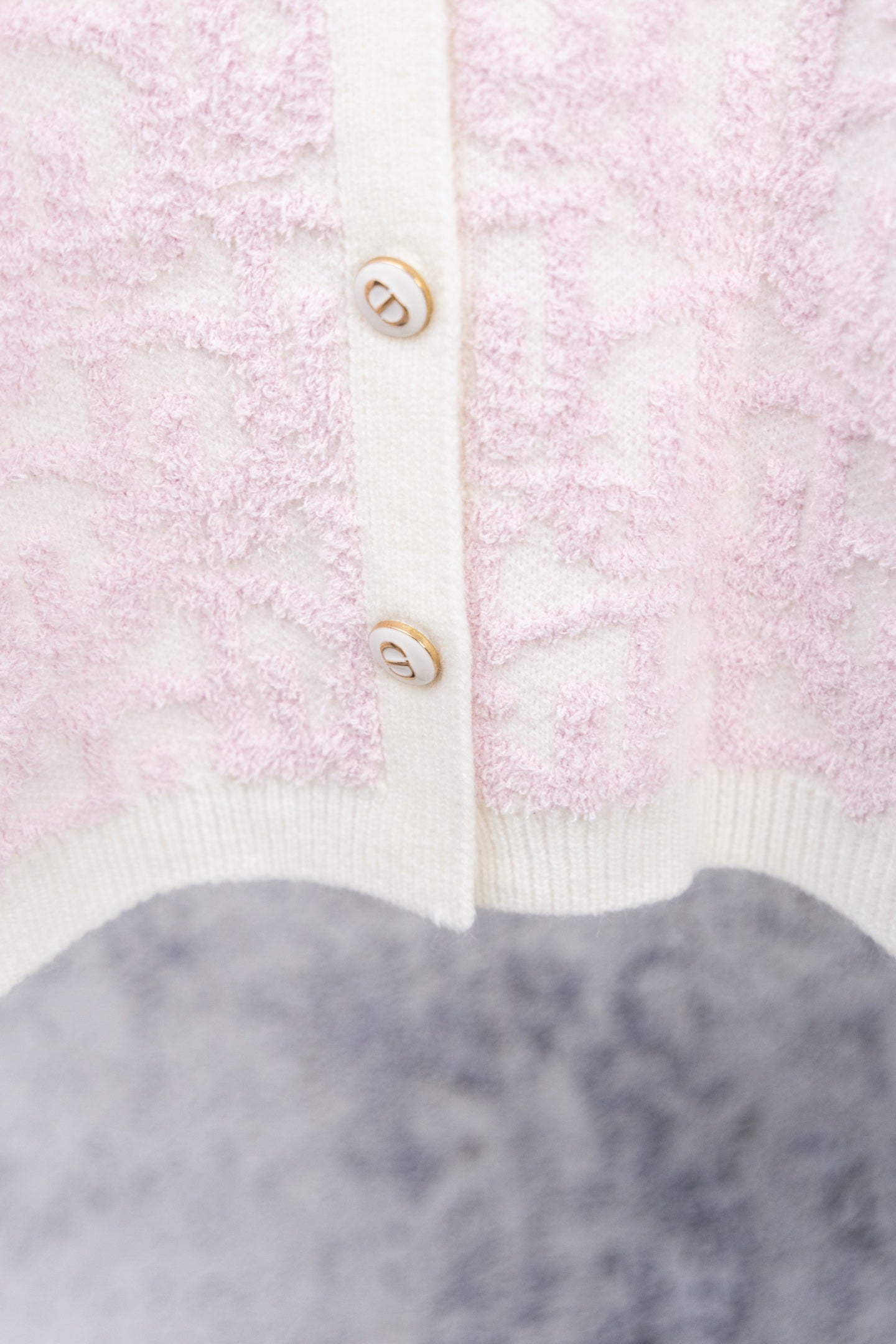 Pale pink textured cardigan with white ribbed hem and button placket