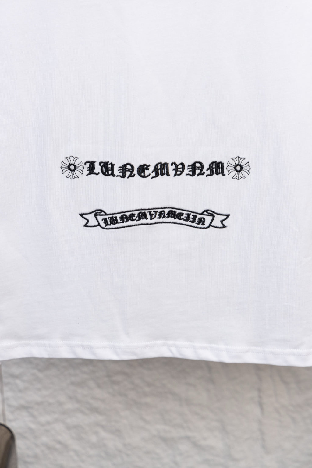 White long-sleeve T-shirt with ornamental ribbon-style text print on the front