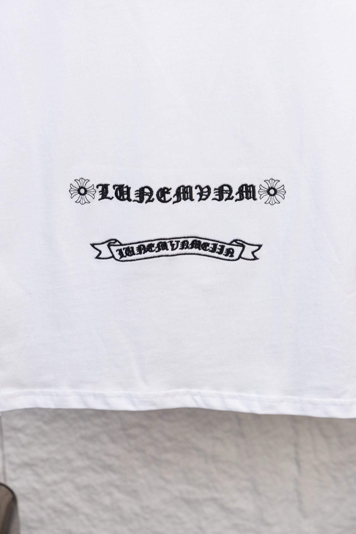 White long-sleeve T-shirt with ornamental ribbon-style text print on the front