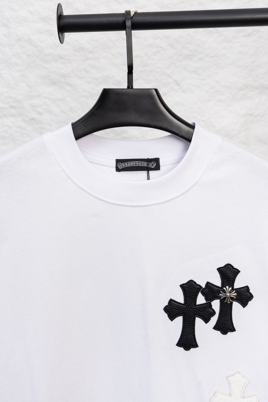 White crewneck T-shirt with three black cross appliques and a light cross