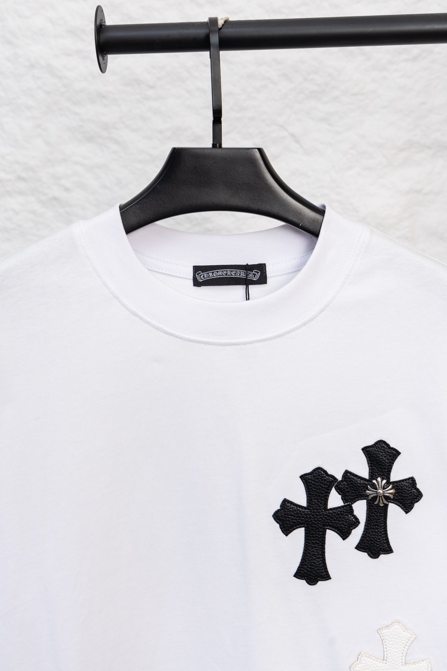 White crewneck T-shirt with three black cross appliques and a light cross
