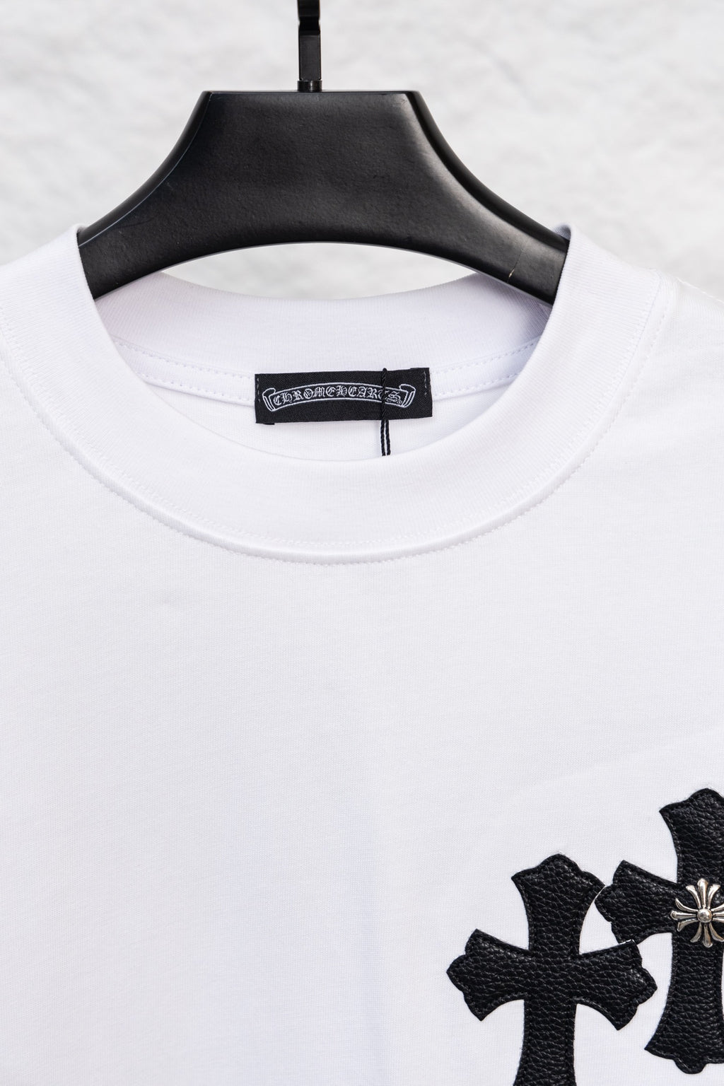 White crewneck long-sleeve T-shirt with partial black cross print at the hem