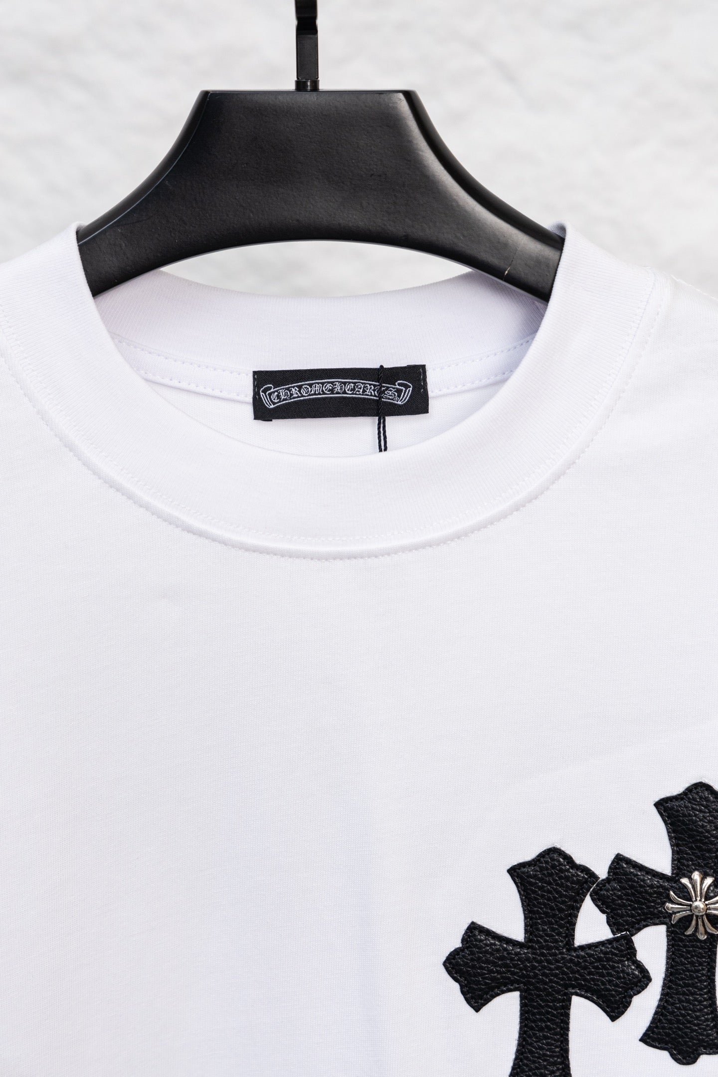 White crewneck long-sleeve T-shirt with partial black cross print at the hem