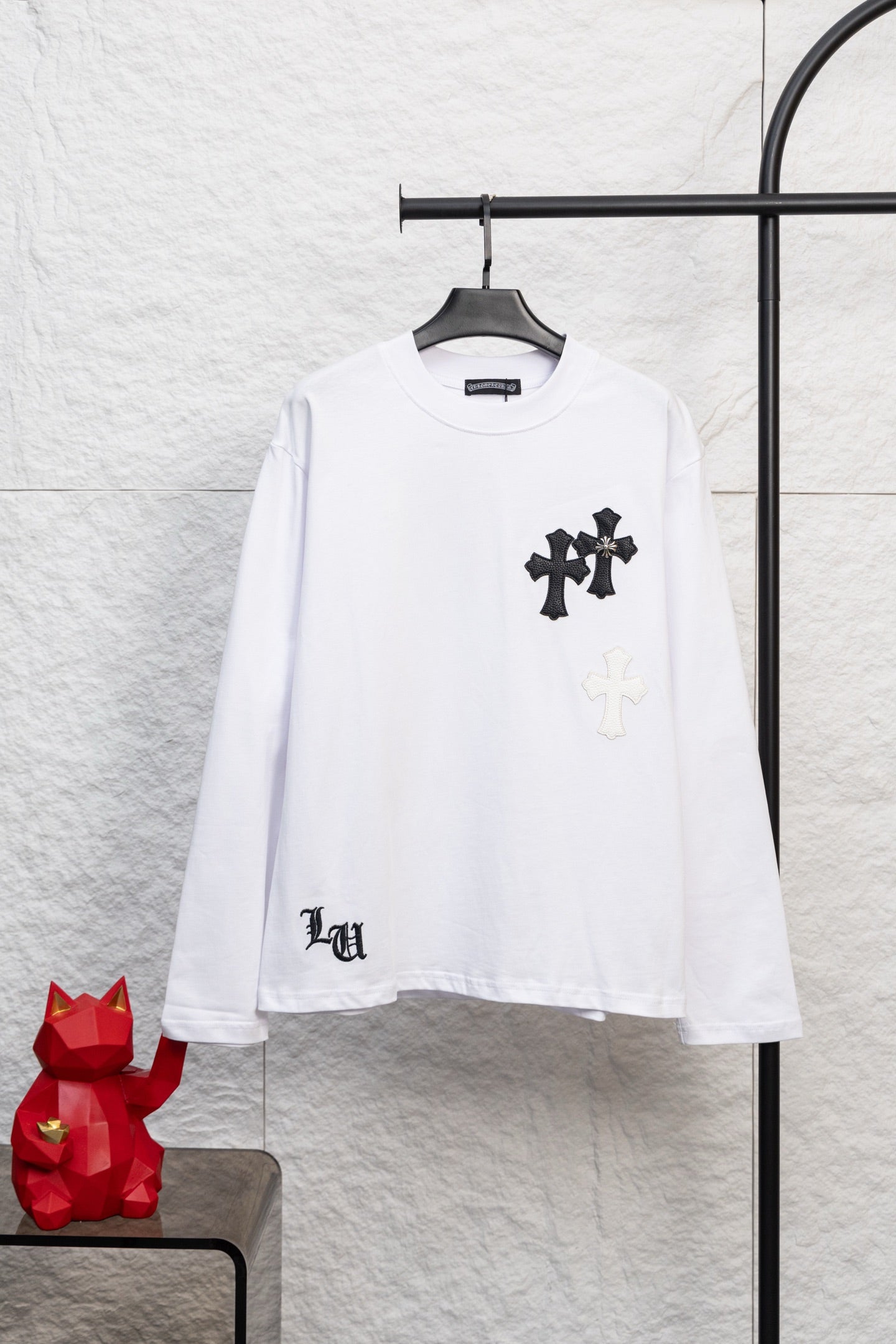 White long-sleeve T-shirt with black cross patch graphic on the chest