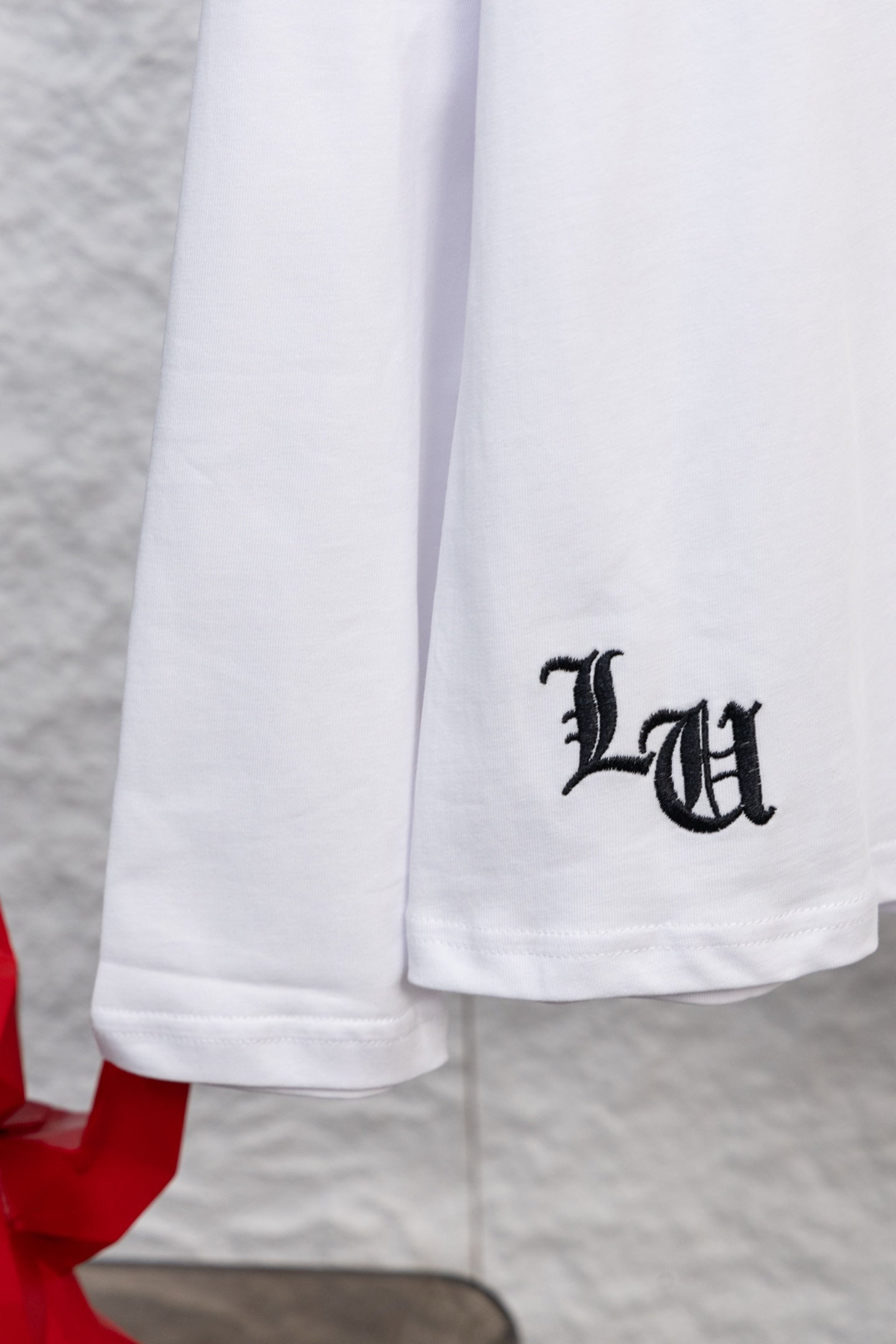 White long-sleeve T-shirt with black "LU" letter print on the lower front