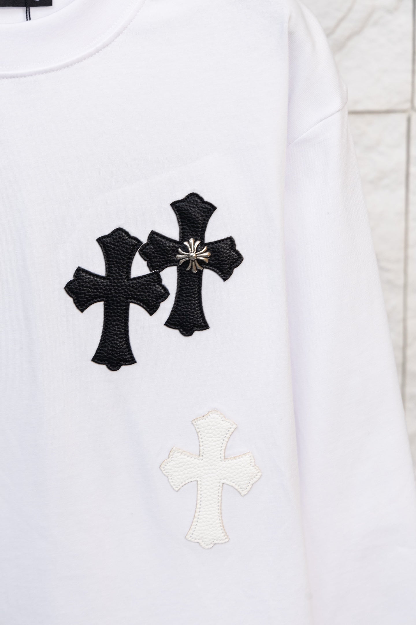 White long-sleeve T-shirt with three black cross appliques and a light cross below