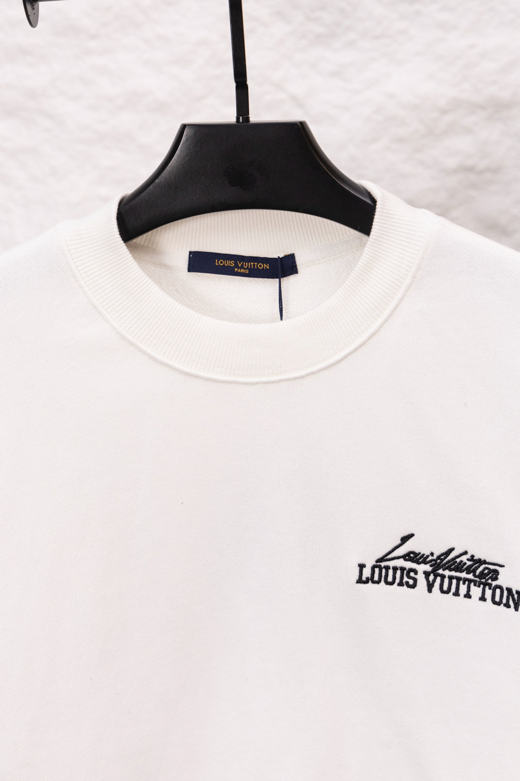 White sweatshirt neckline with small Louis Vuitton logo on the side