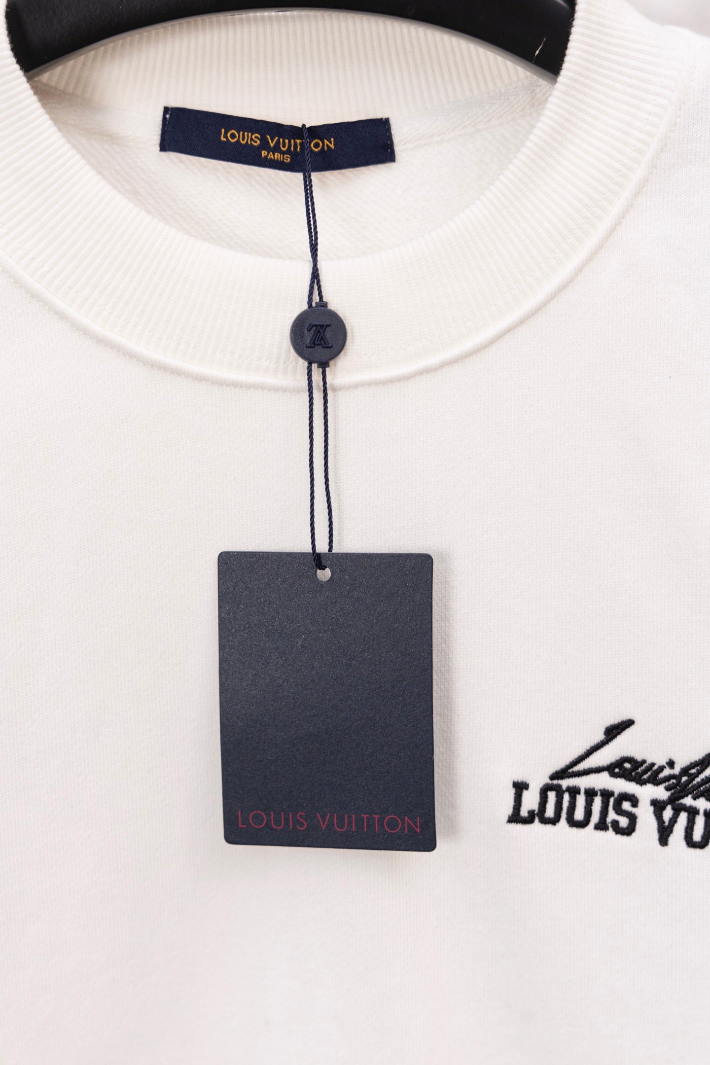 White sweatshirt neckline with blue Louis Vuitton tag and inner label