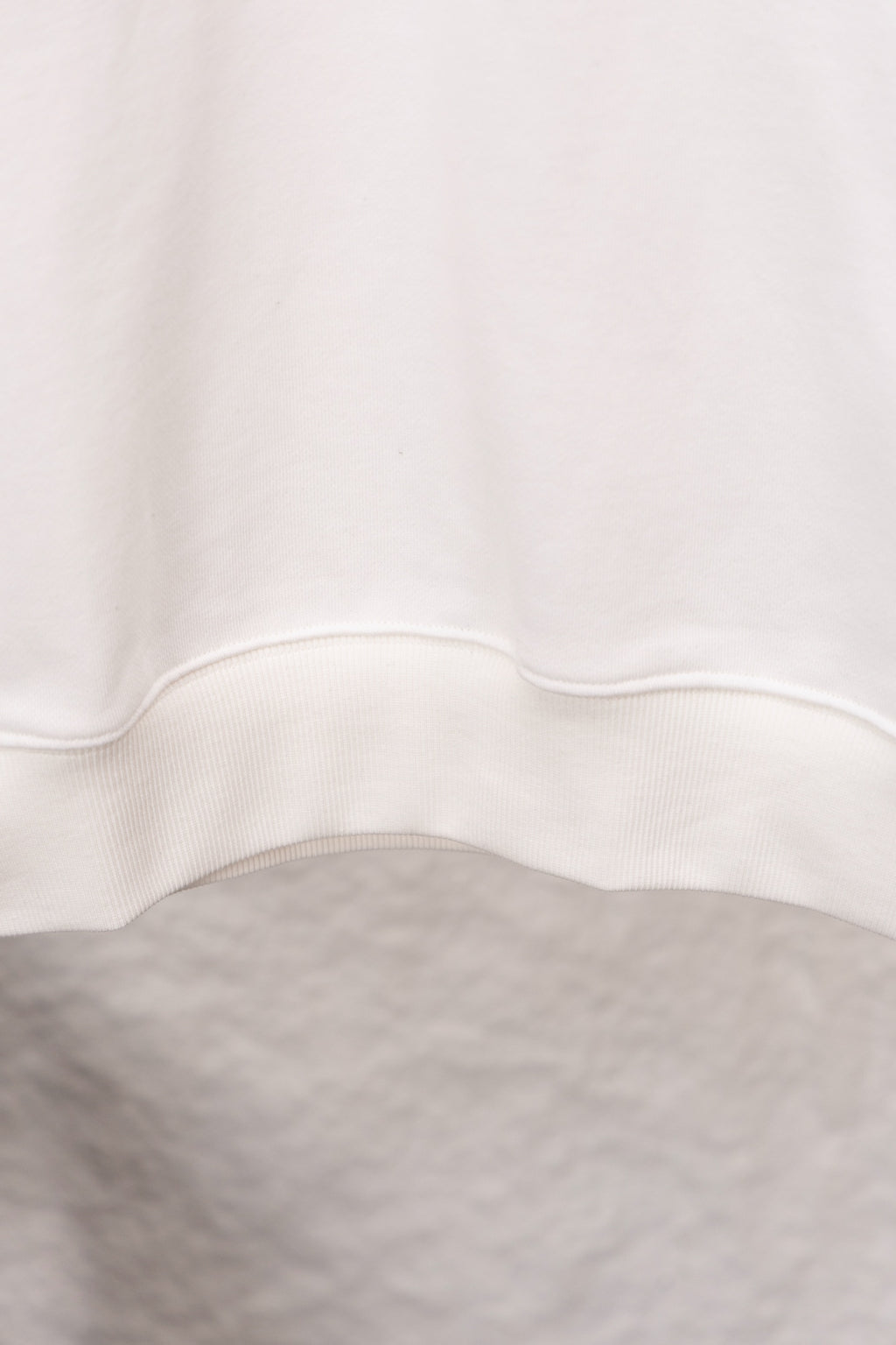 White sweatshirt hem with ribbed trim at the bottom