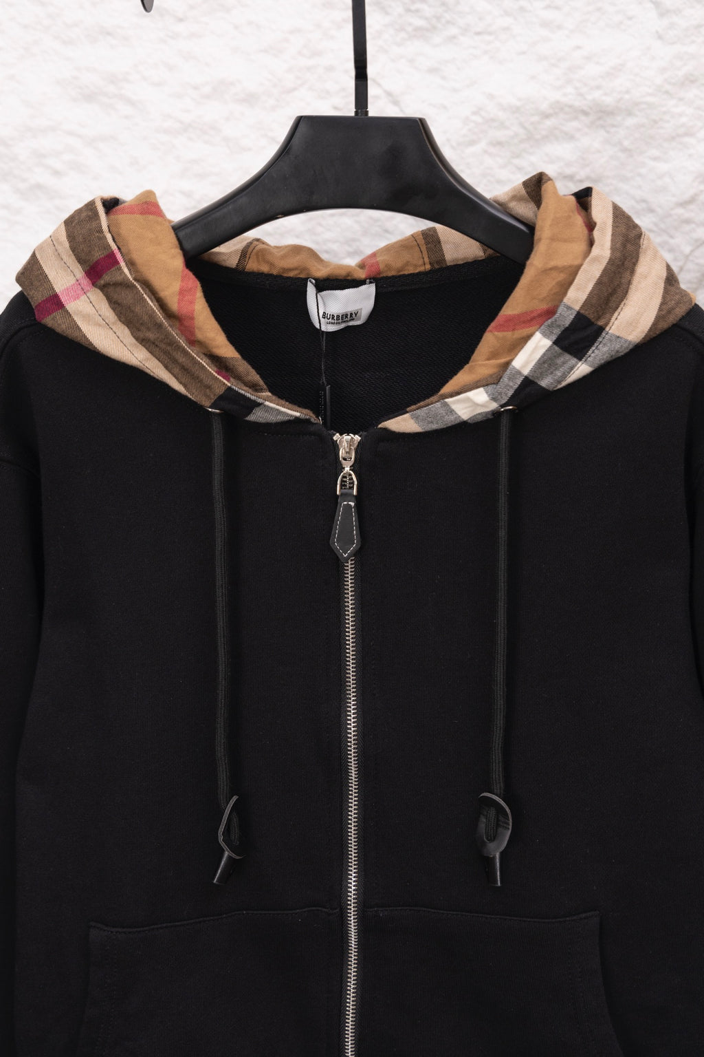 Black zip hoodie with plaid-lined hood, front zipper, and drawstrings