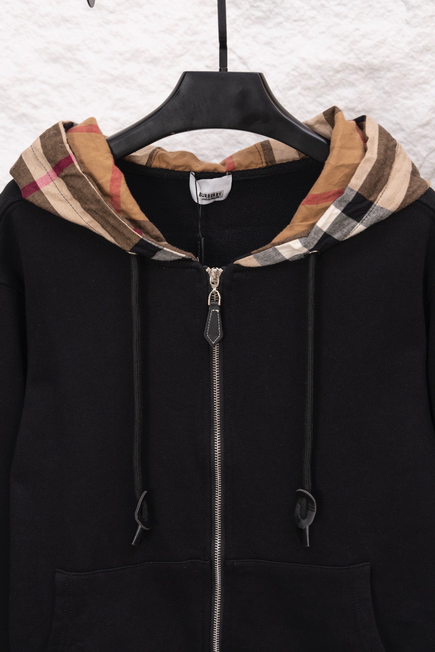Black zip hoodie with plaid-lined hood, front zipper, and drawstrings