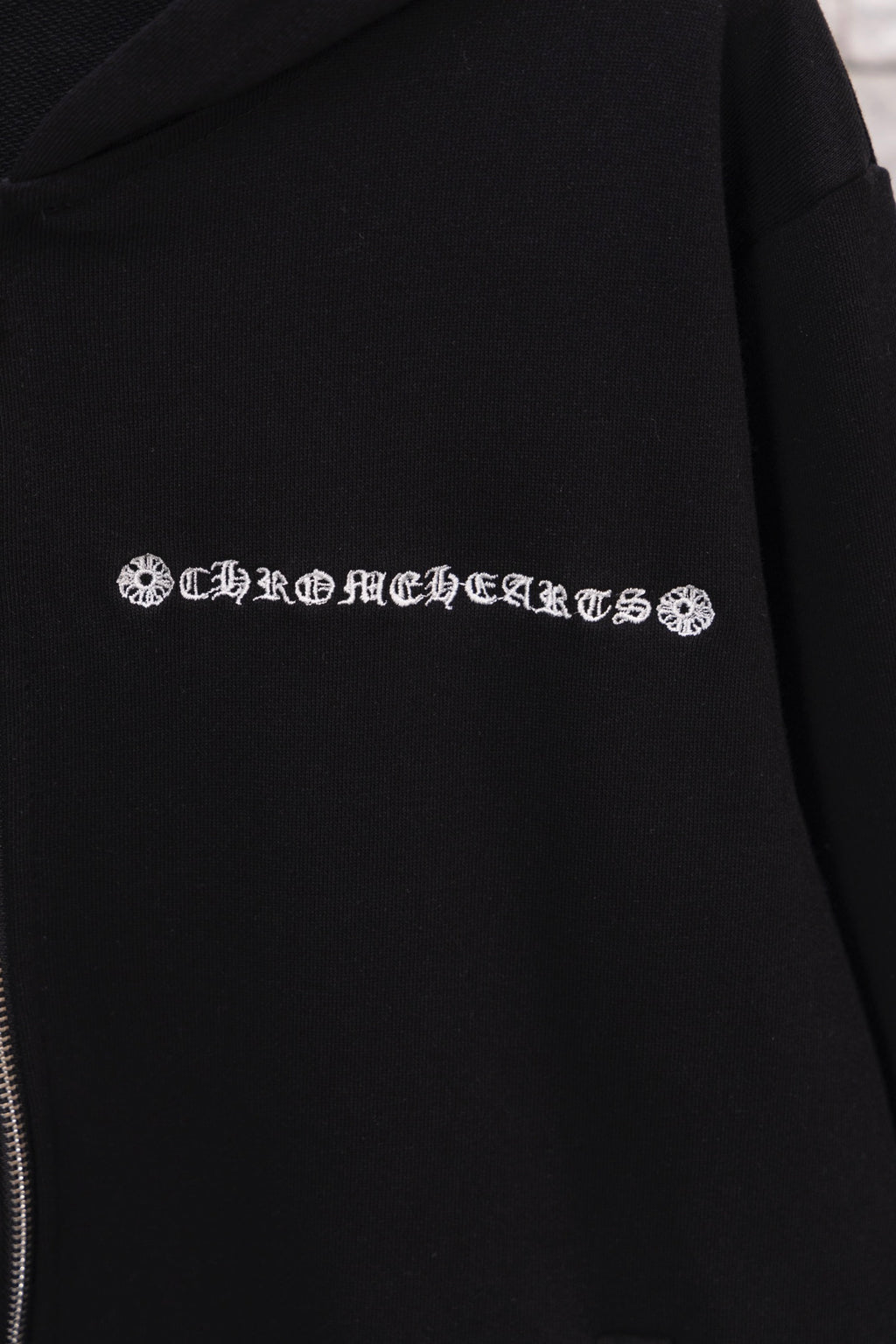 Black hoodie with embroidered logo text detail across the chest