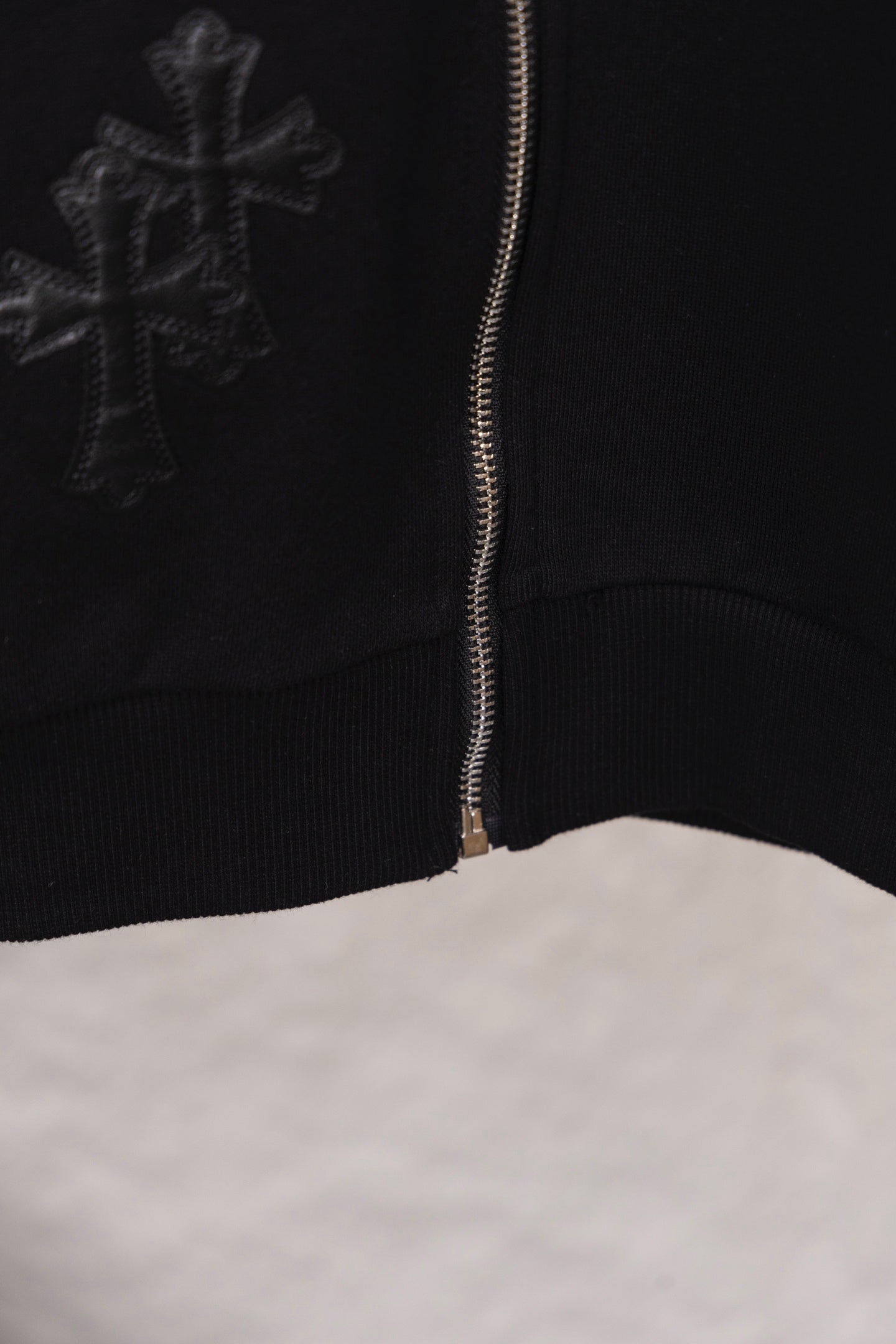 Black zip-up hoodie with cross graphic and front zipper