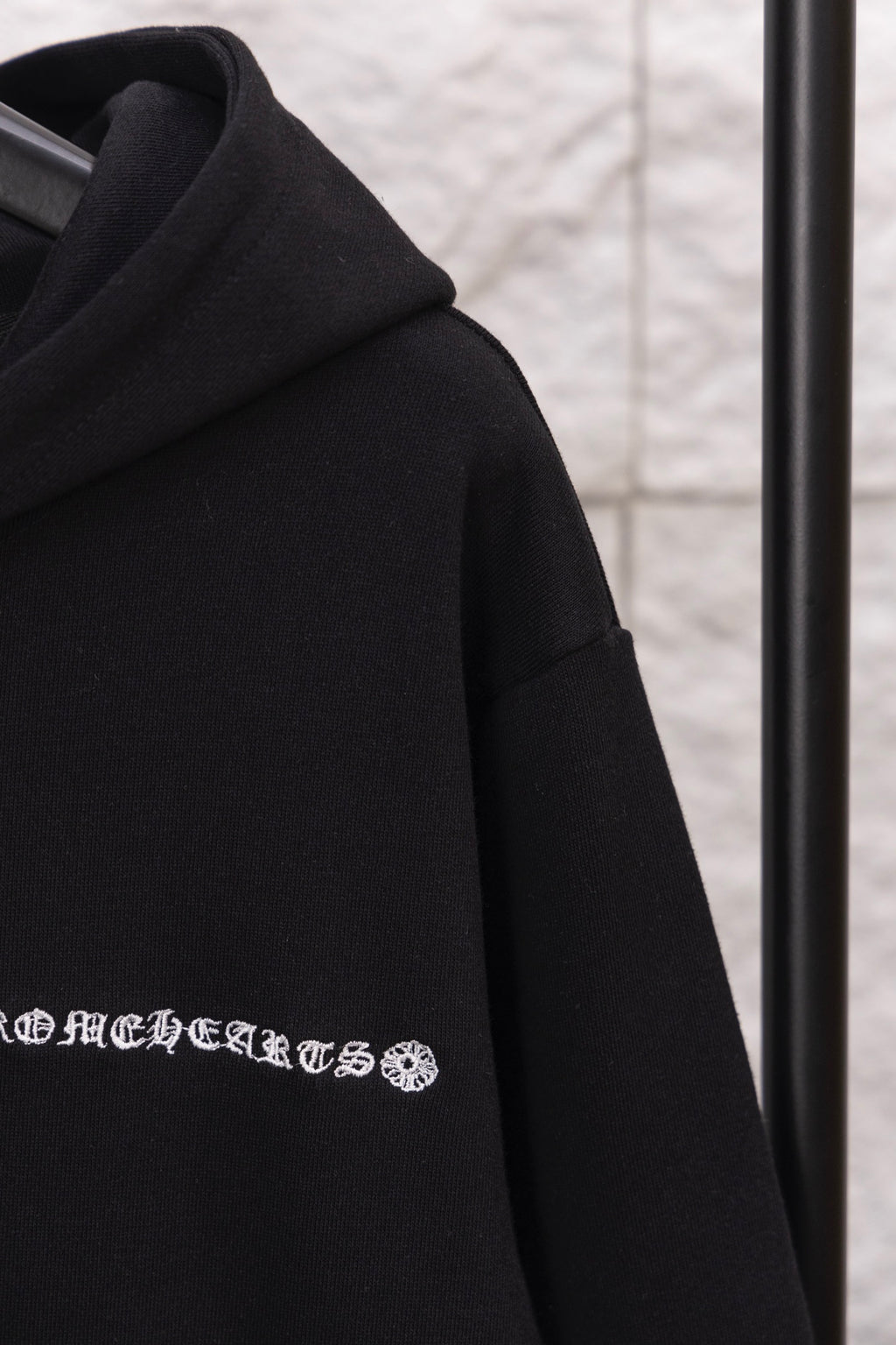 Black hoodie shoulder and hood seam; embroidered logo graphic near chest