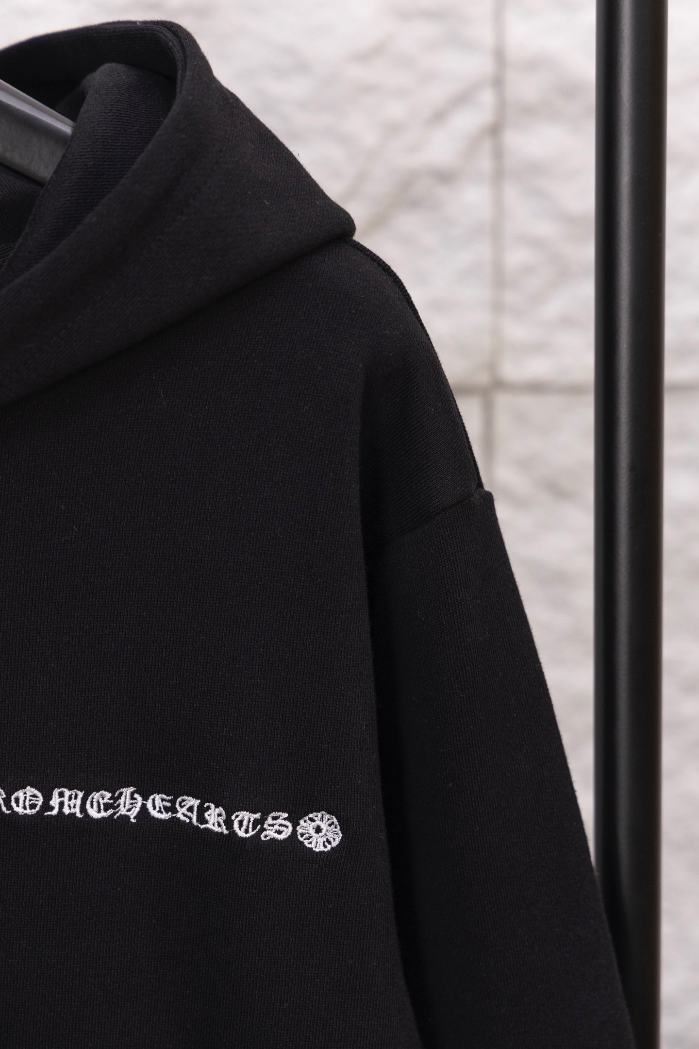 Black hoodie shoulder and hood seam; embroidered logo graphic near chest