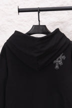Black hoodie with hood and embroidered cross emblem on the upper sleeve
