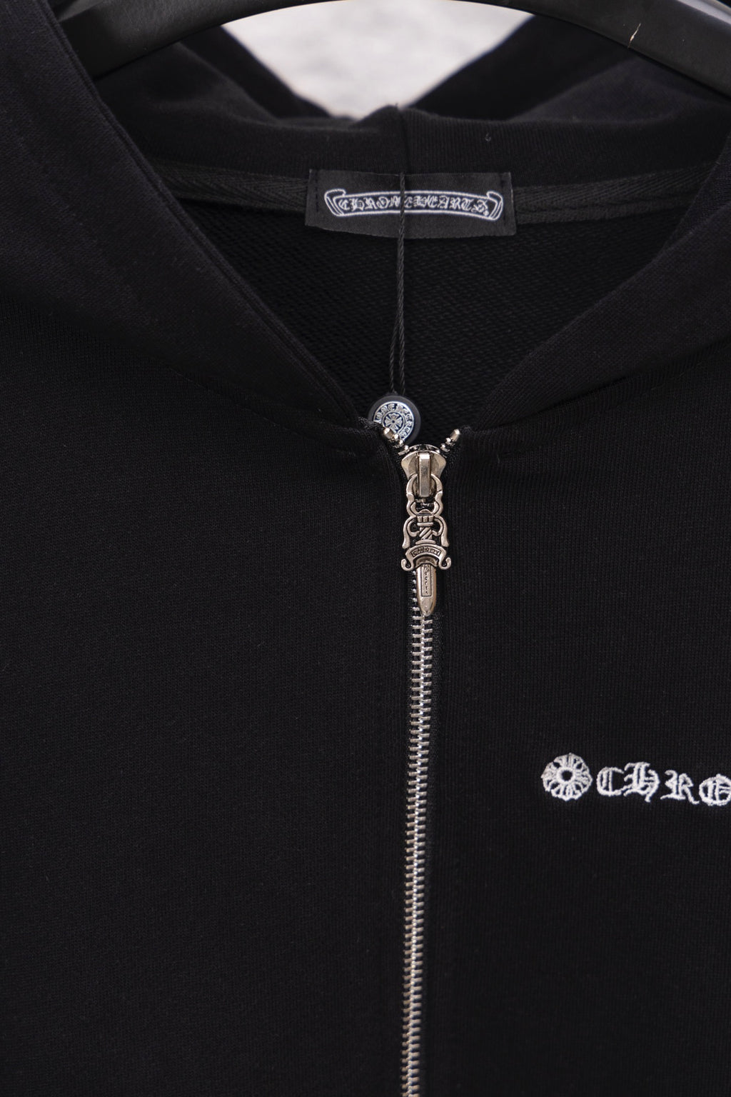 Black hoodie with zipper and hood pull charm; logo graphic on right chest