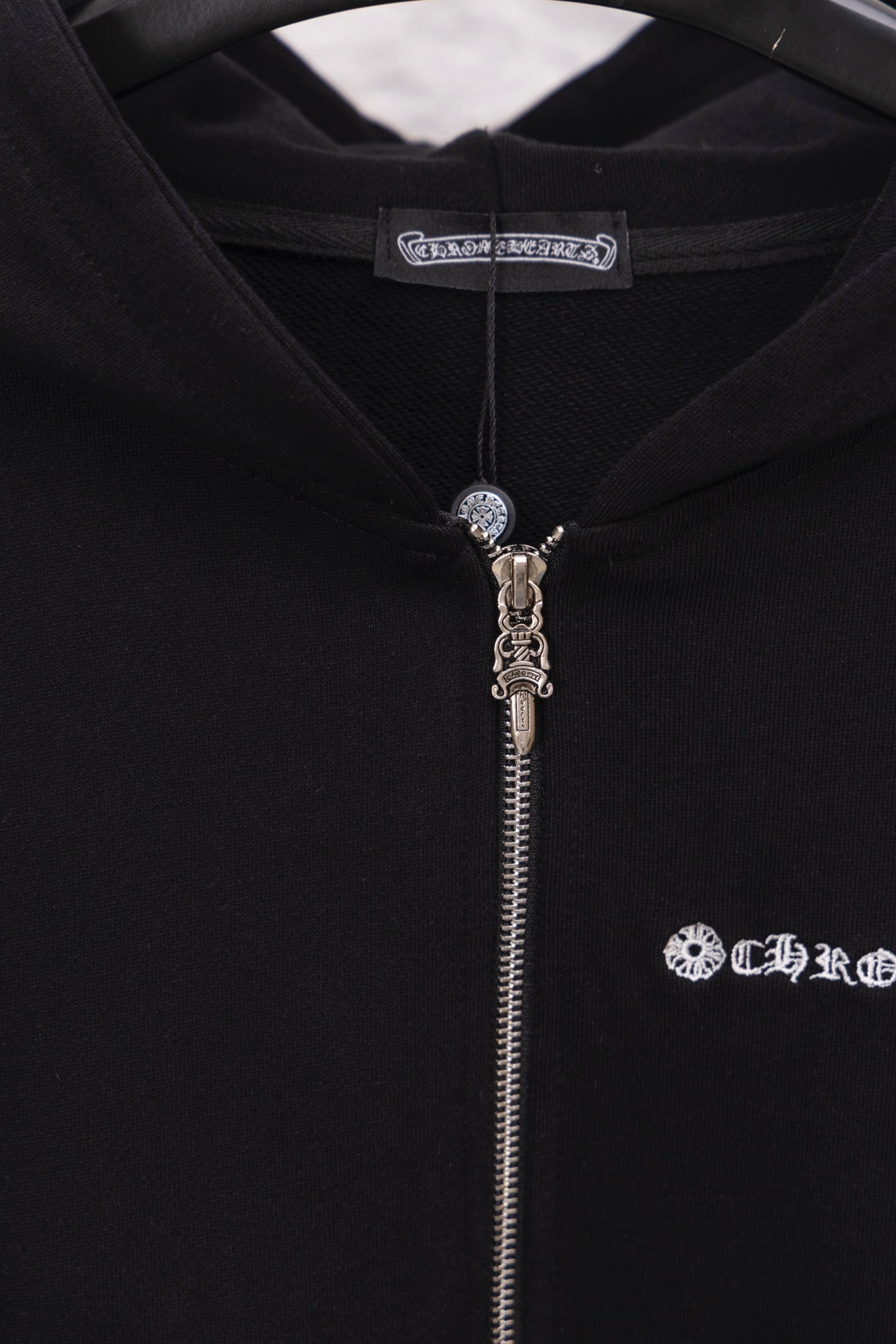 Black hoodie with zipper and hood pull charm; logo graphic on right chest