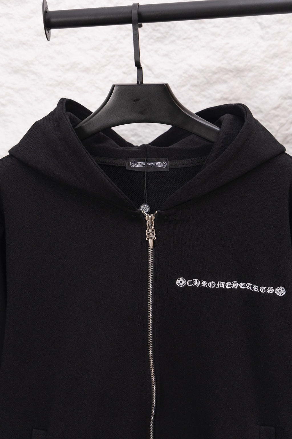 Black zip-up hoodie with hood and metal-tone zipper pull; logo graphic on chest