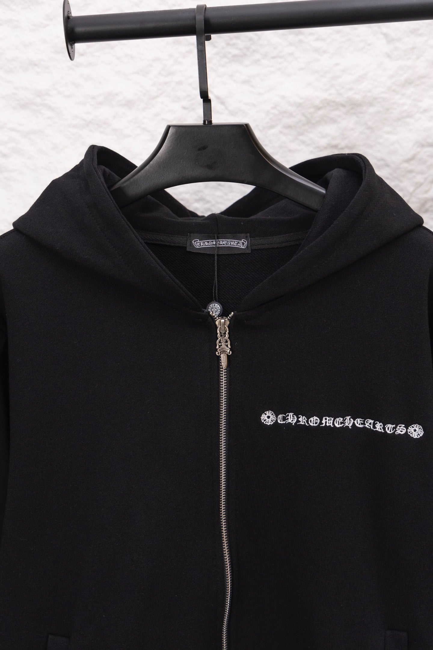 Black zip-up hoodie with hood and metal-tone zipper pull; logo graphic on chest