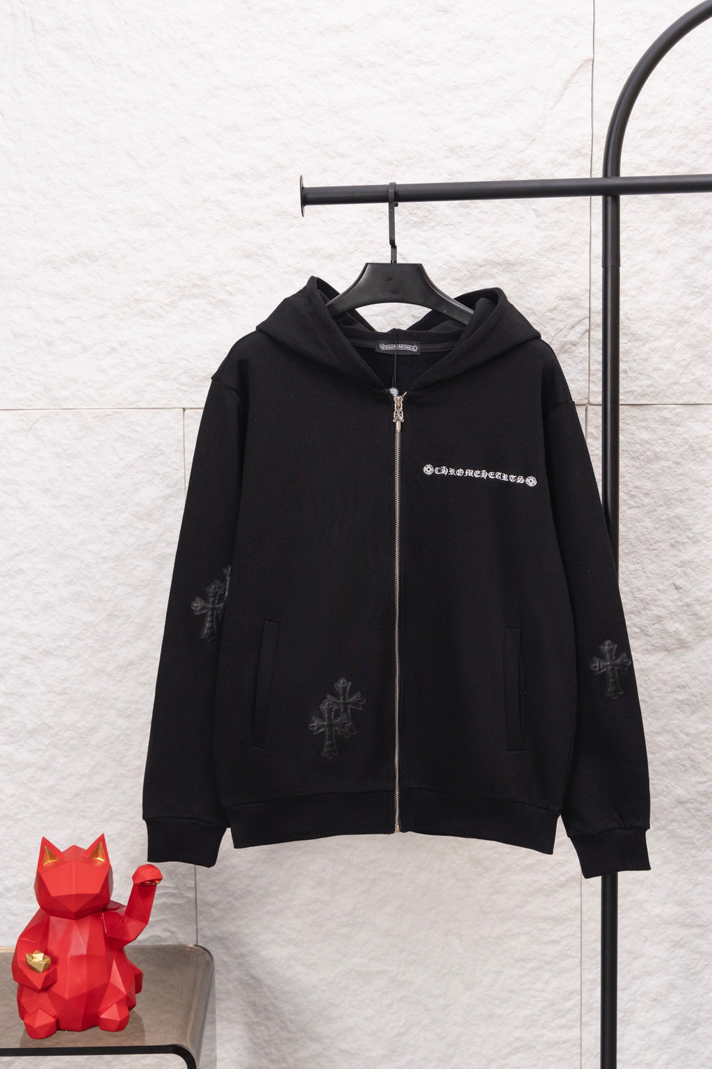 Black zip-up hoodie with hood, front zipper, and small logo graphic at chest