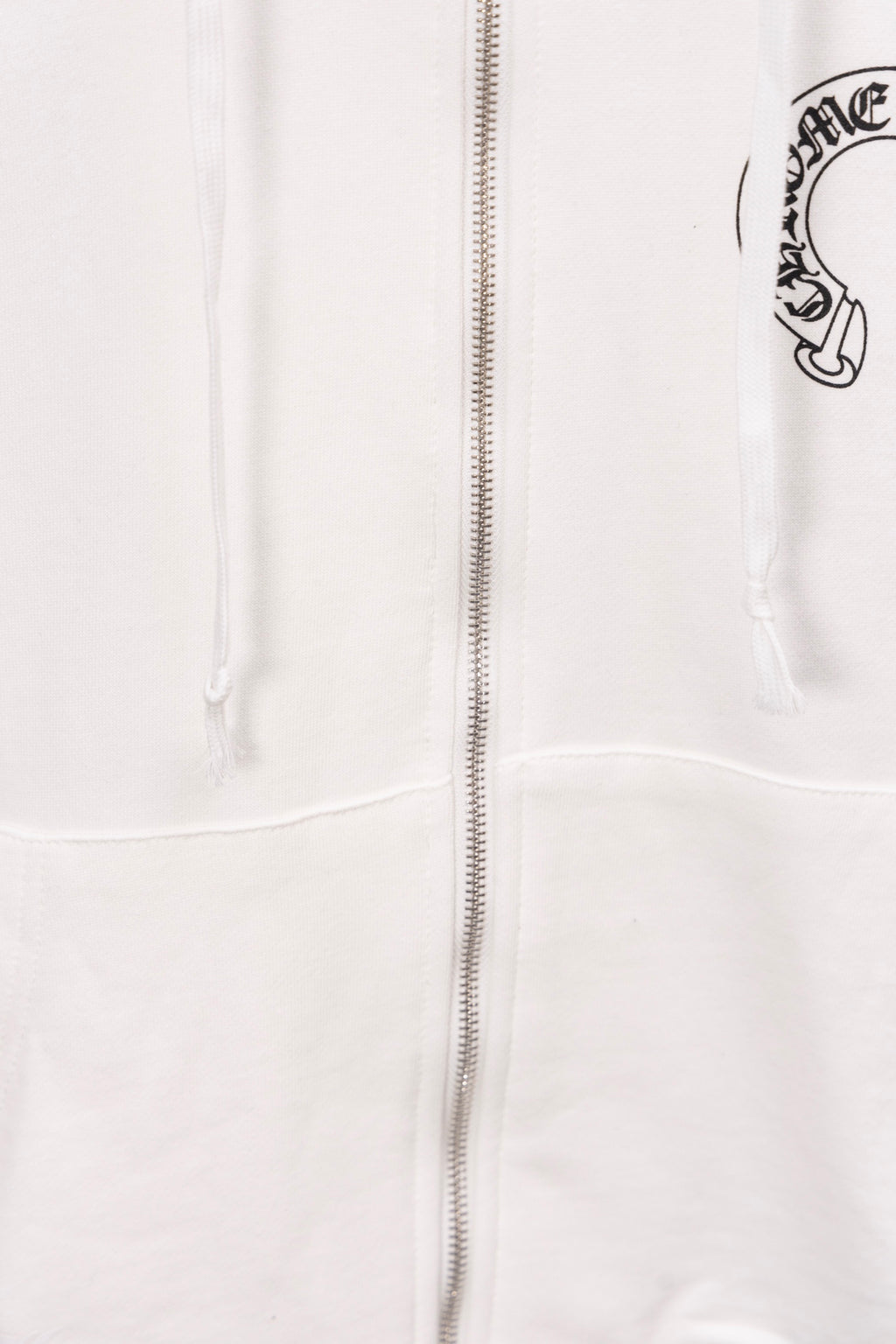 White zip-up hoodie close-up showing center zipper and drawstrings