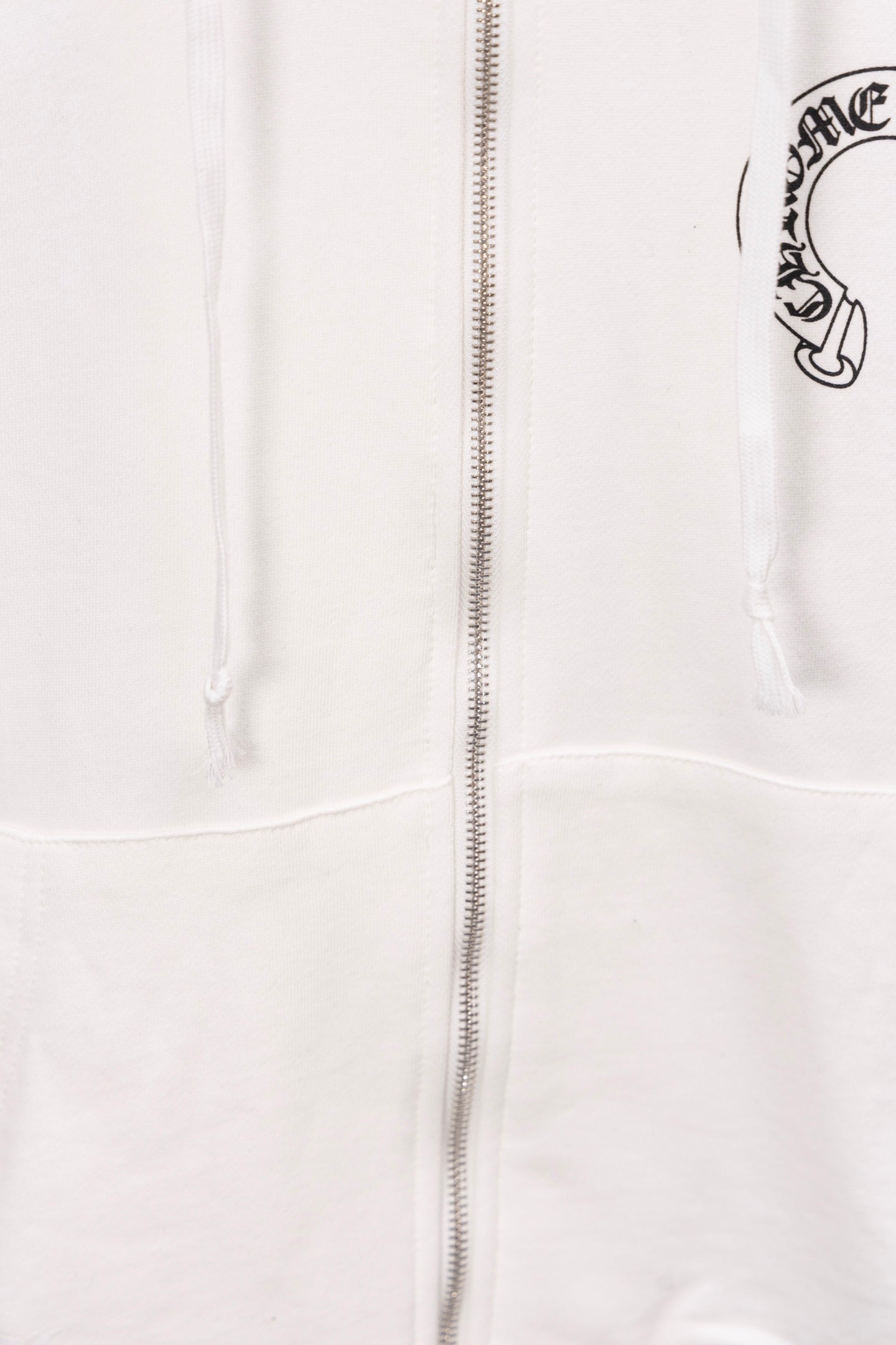White zip-up hoodie close-up showing center zipper and drawstrings