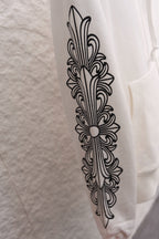 White hoodie sleeve with vertical fleur-de-lis line art graphic
