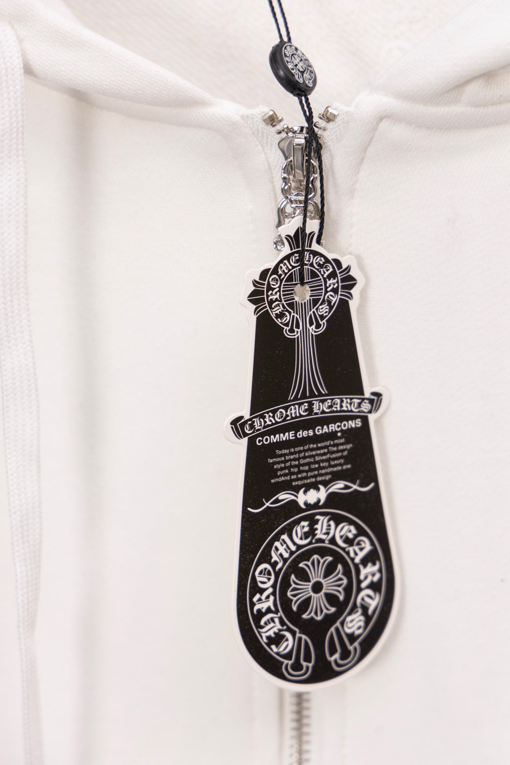 White hoodie zipper pull with ornate crest and shield design