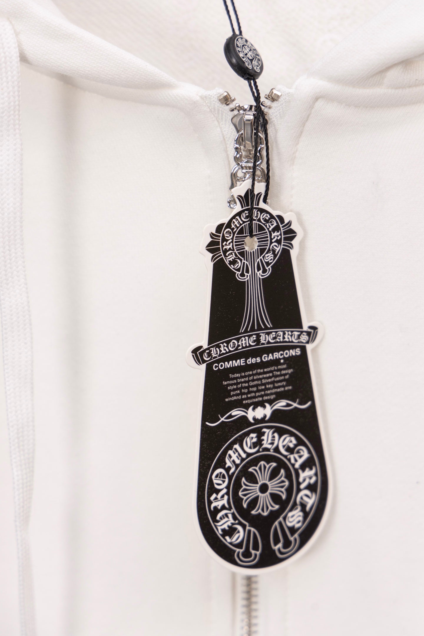 White hoodie zipper pull with ornate crest and shield design