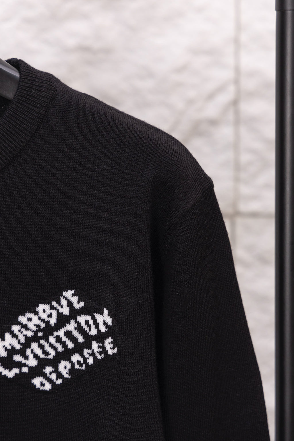 Black long-sleeve sweatshirt sleeve with partial white logo text print