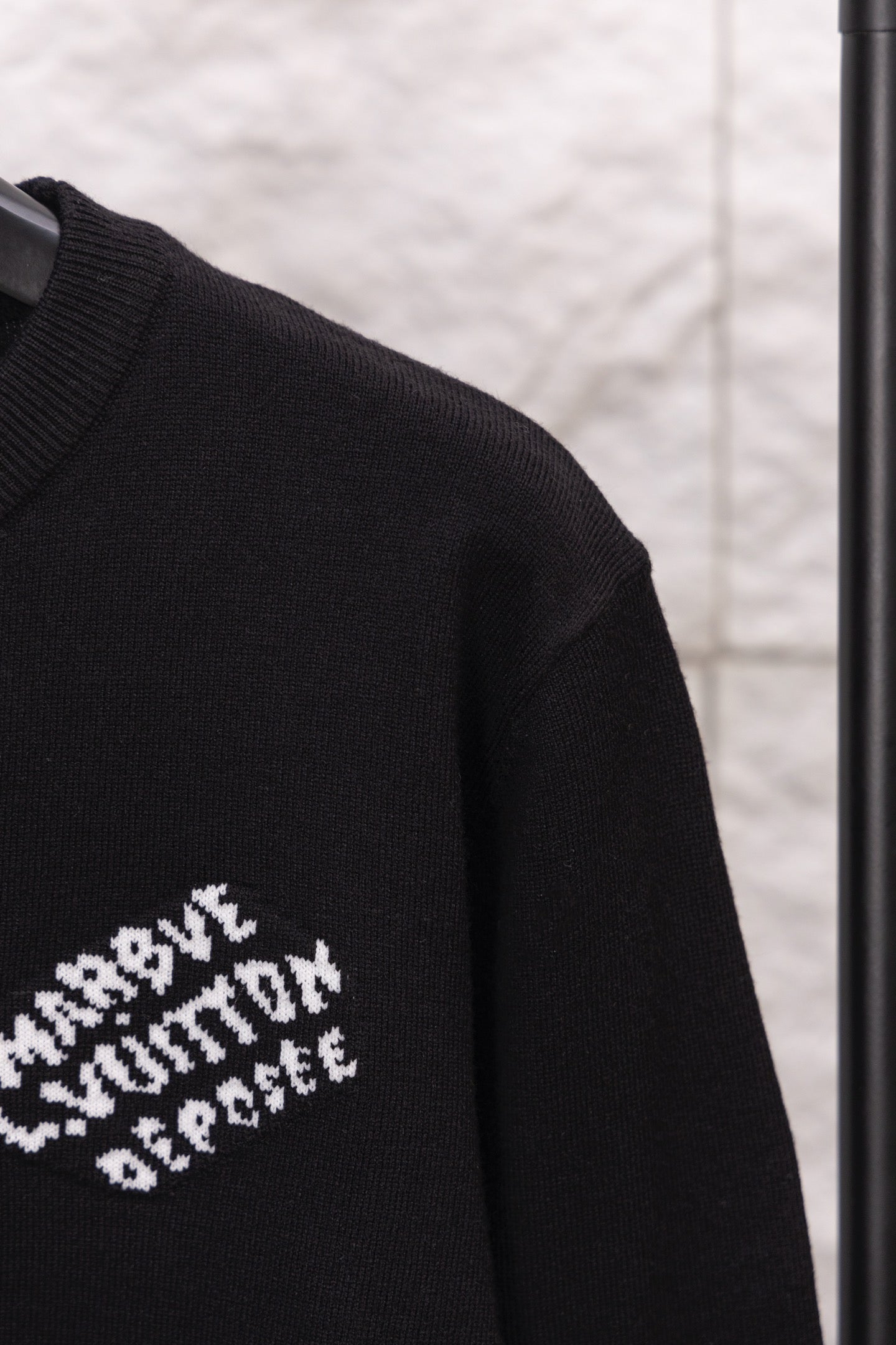 Black long-sleeve sweatshirt sleeve with partial white logo text print