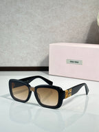 Black cat-eye sunglasses with warm tinted lenses and gold temple logo