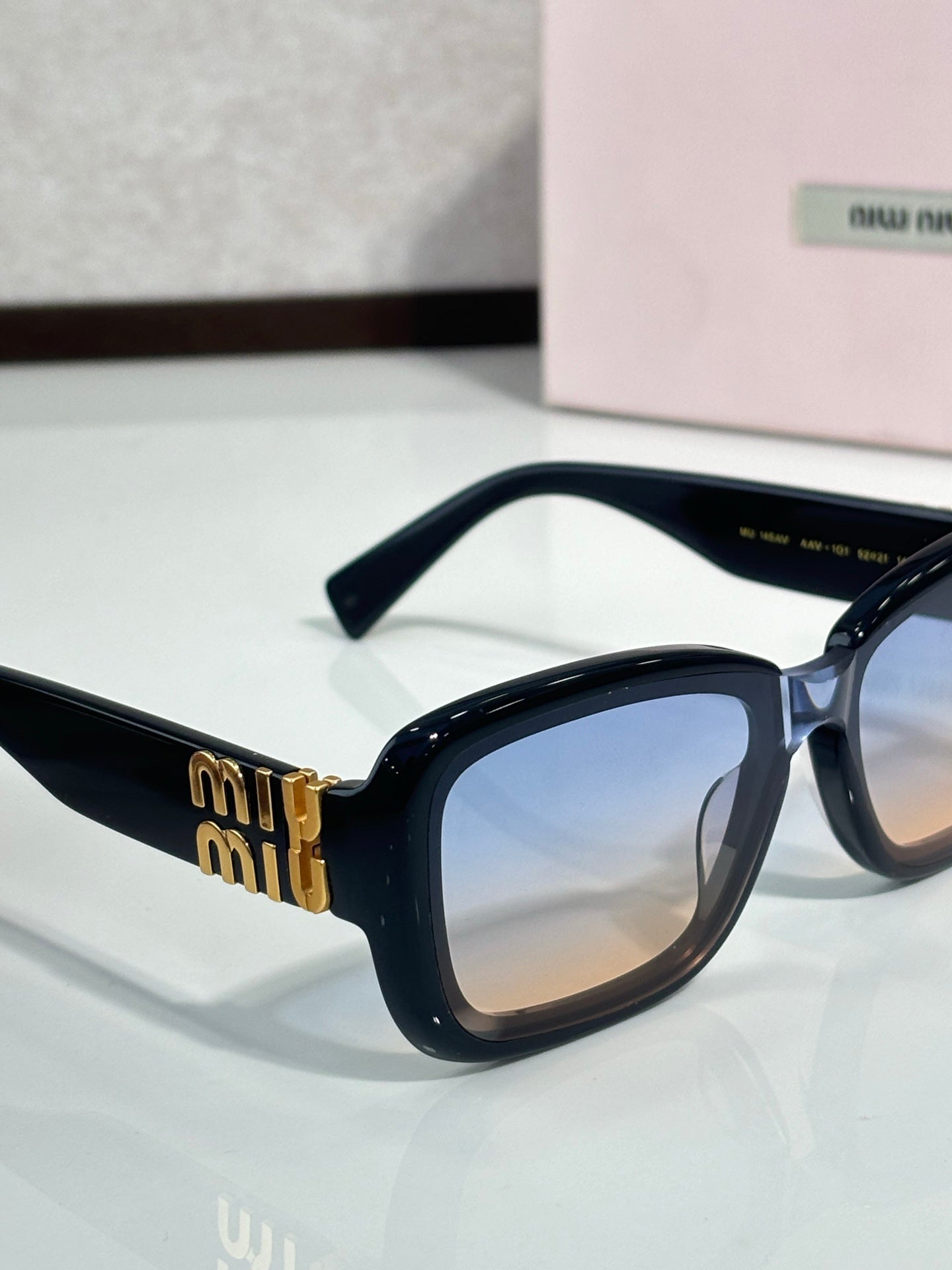 Black cat-eye sunglasses with gradient lenses and gold logo on temple