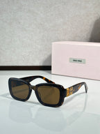 Black cat-eye sunglasses with brown tinted lenses and gold temple lettering