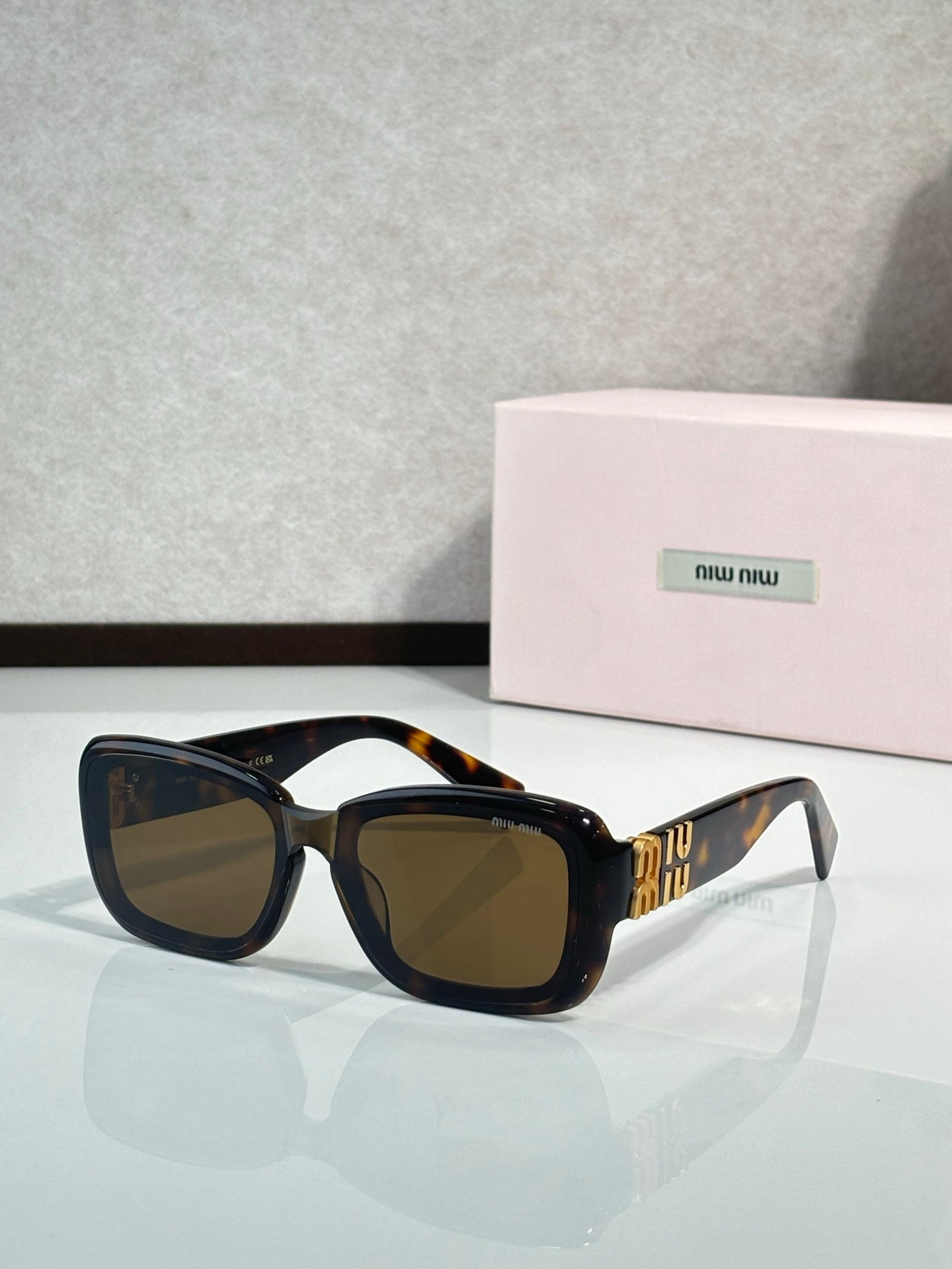 Black cat-eye sunglasses with brown tinted lenses and gold temple lettering