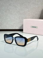Black cat-eye sunglasses with blue lenses and gold temple logo detail