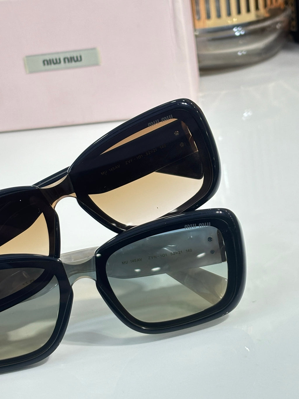 Black sunglasses with gold logo temples and tinted lenses close-up