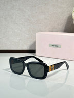 Black cat-eye sunglasses with dark lenses and gold temple branding
