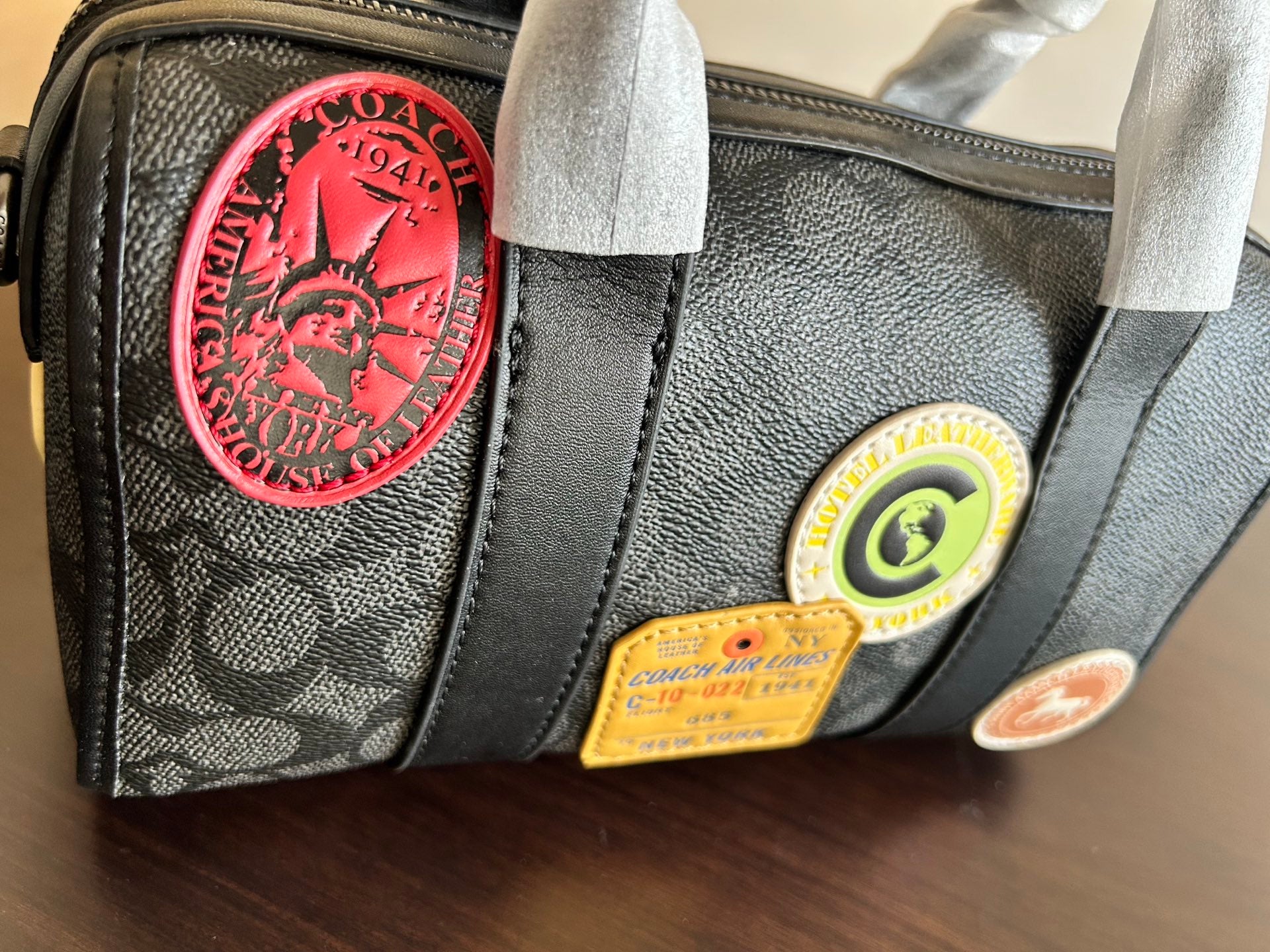 Coah bag close-up of side badges, black fabric with leather trim and zipper pull