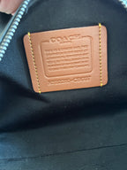 Coah bag leather brand label patch with printed serial text on dark fabric