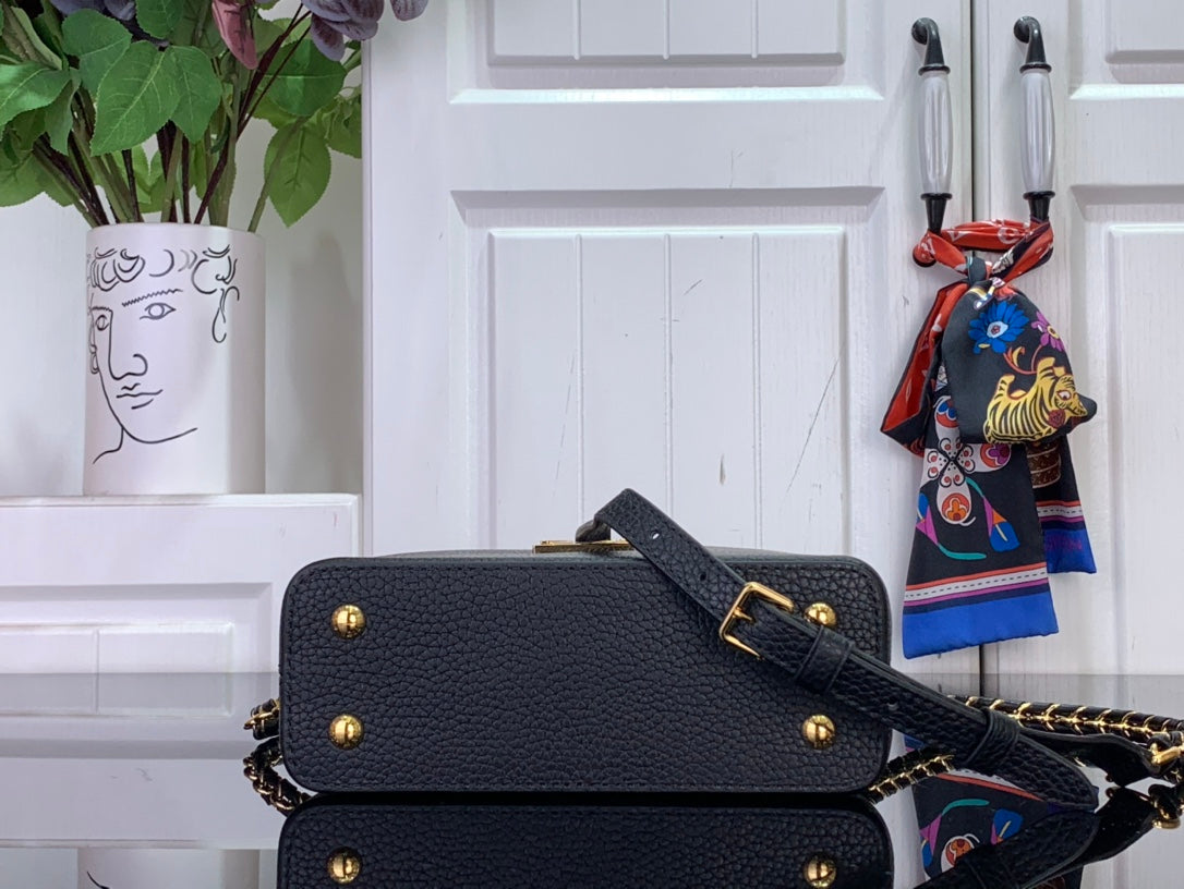 Louis Vuitton black crossbody flap bag with gold snap, chain strap, and stud accents
