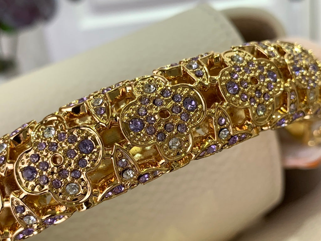 Decorative gold-toned trim with purple and clear stones, set along the bag edge
