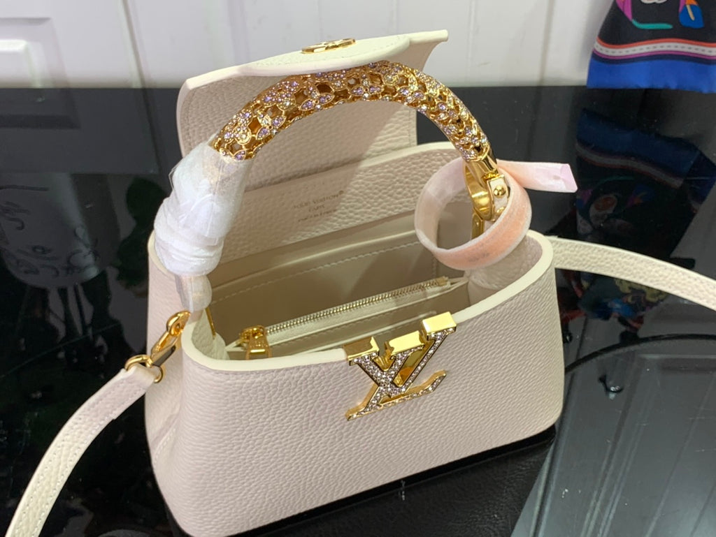 White textured handbag with open top, gold hardware, and thin shoulder strap