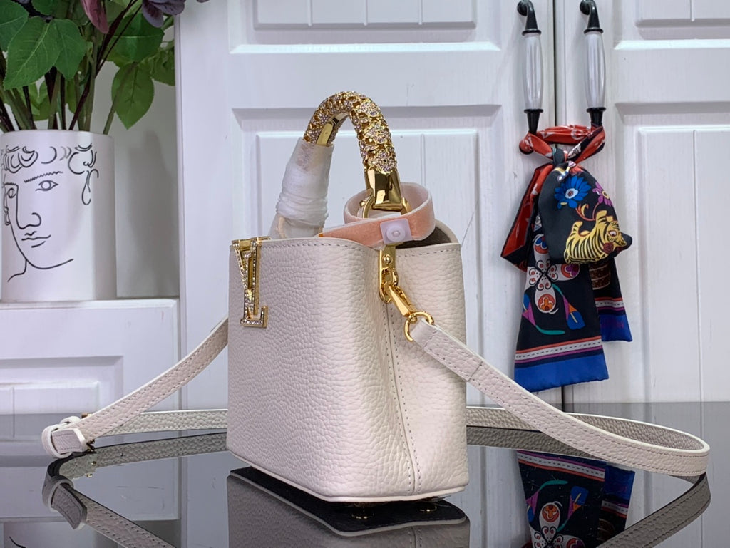 White textured handbag with gold hardware, top handle, and long crossbody strap