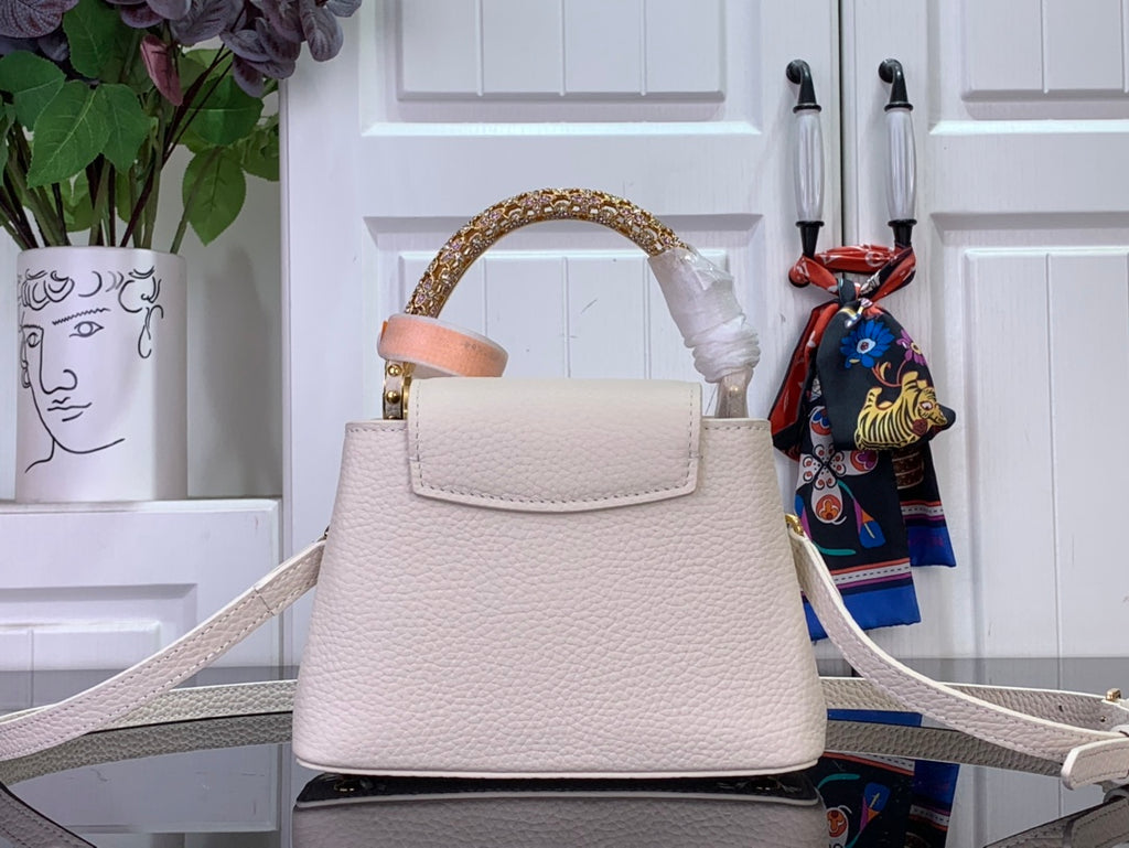 White textured handbag with gold top handle and crossbody strap, front flap detail