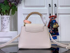 White textured handbag with gold top handle and crossbody strap, front flap detail