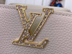 White textured handbag with large gold LV logo embellished with purple stones