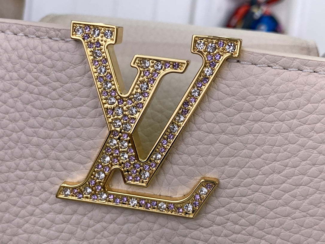 White textured handbag with large gold LV logo embellished with purple stones